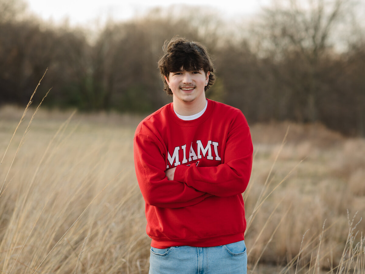 male high school senior in red sweatshirt posed at Westcreek reservation for senior portraits
