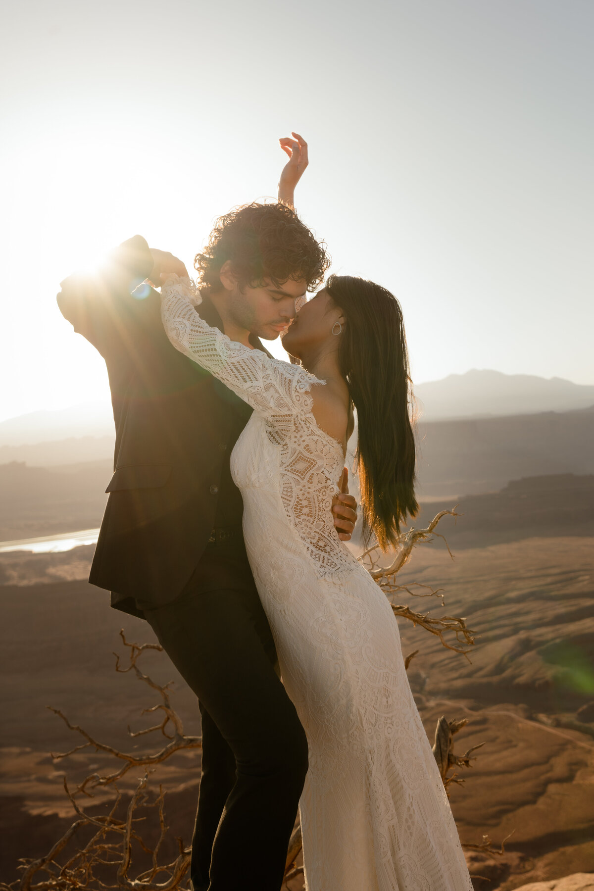 Bride and groom in Moab at sunrise eloping with Claire Pettibone gown the light coming behind them to case a silhouette