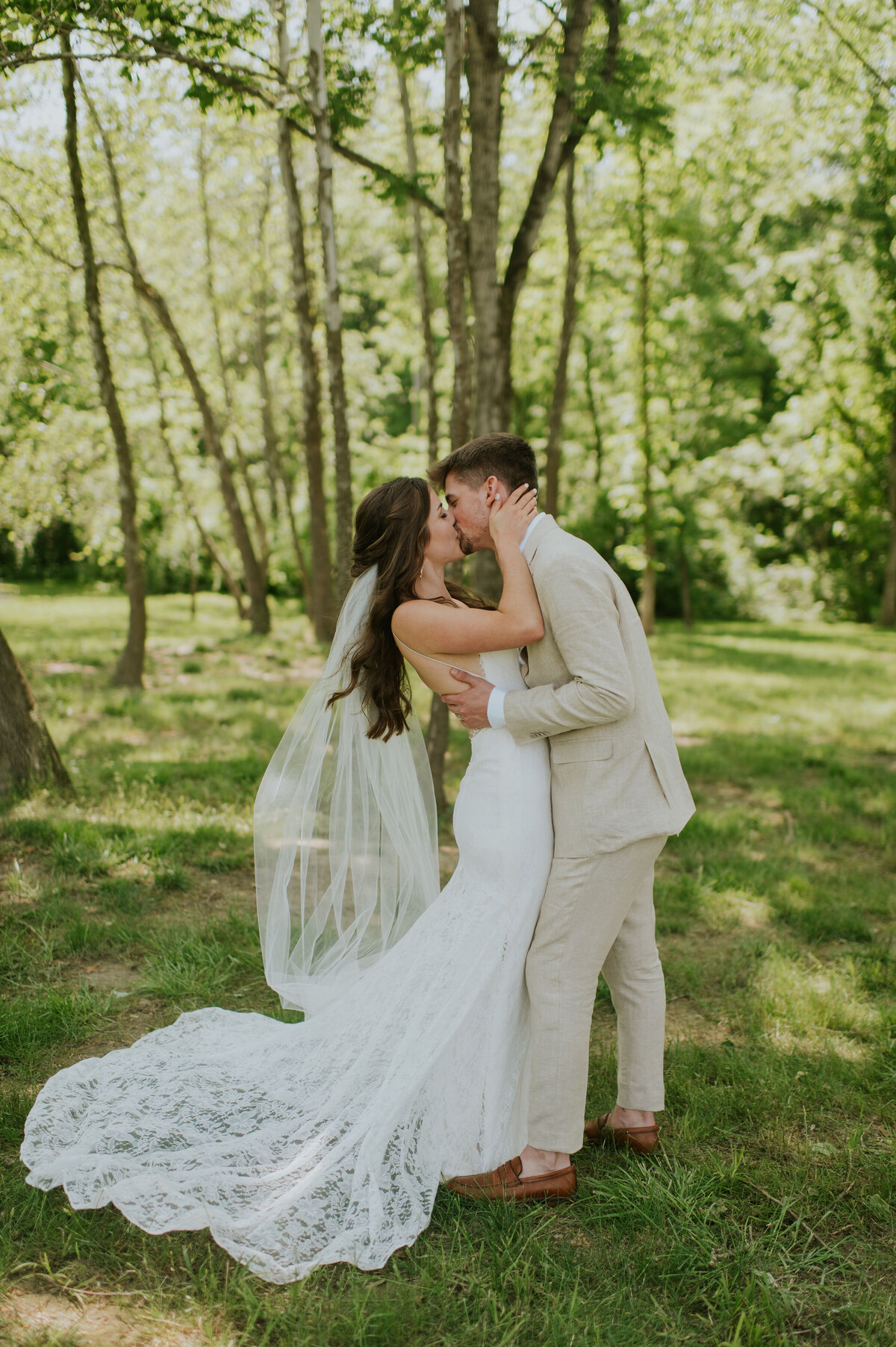 Bride with veil kissing Groom in forest South Bend