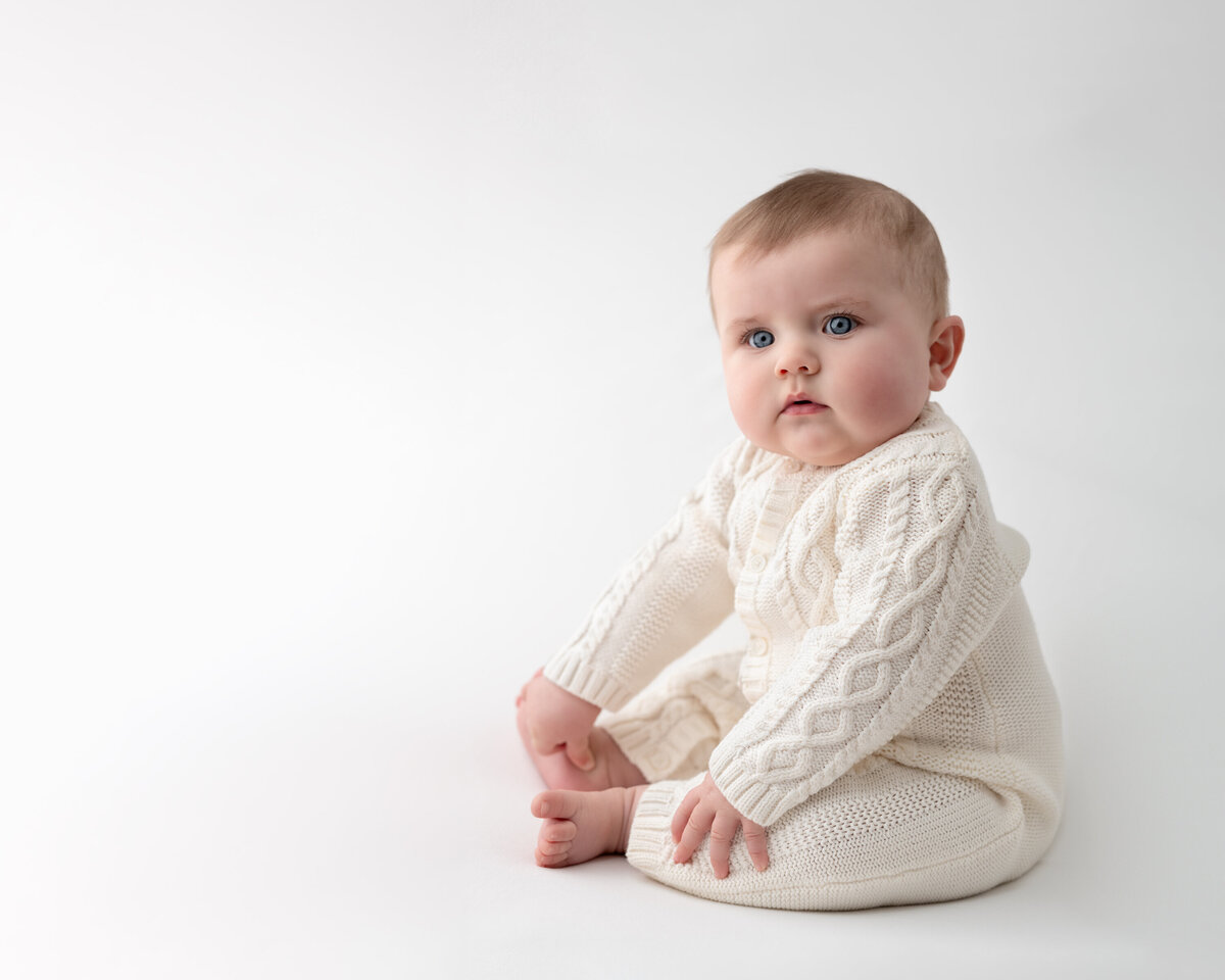 Classic sitter milestone portrait of a baby in cable knit cream—clean, pure, and beautifully timeless.