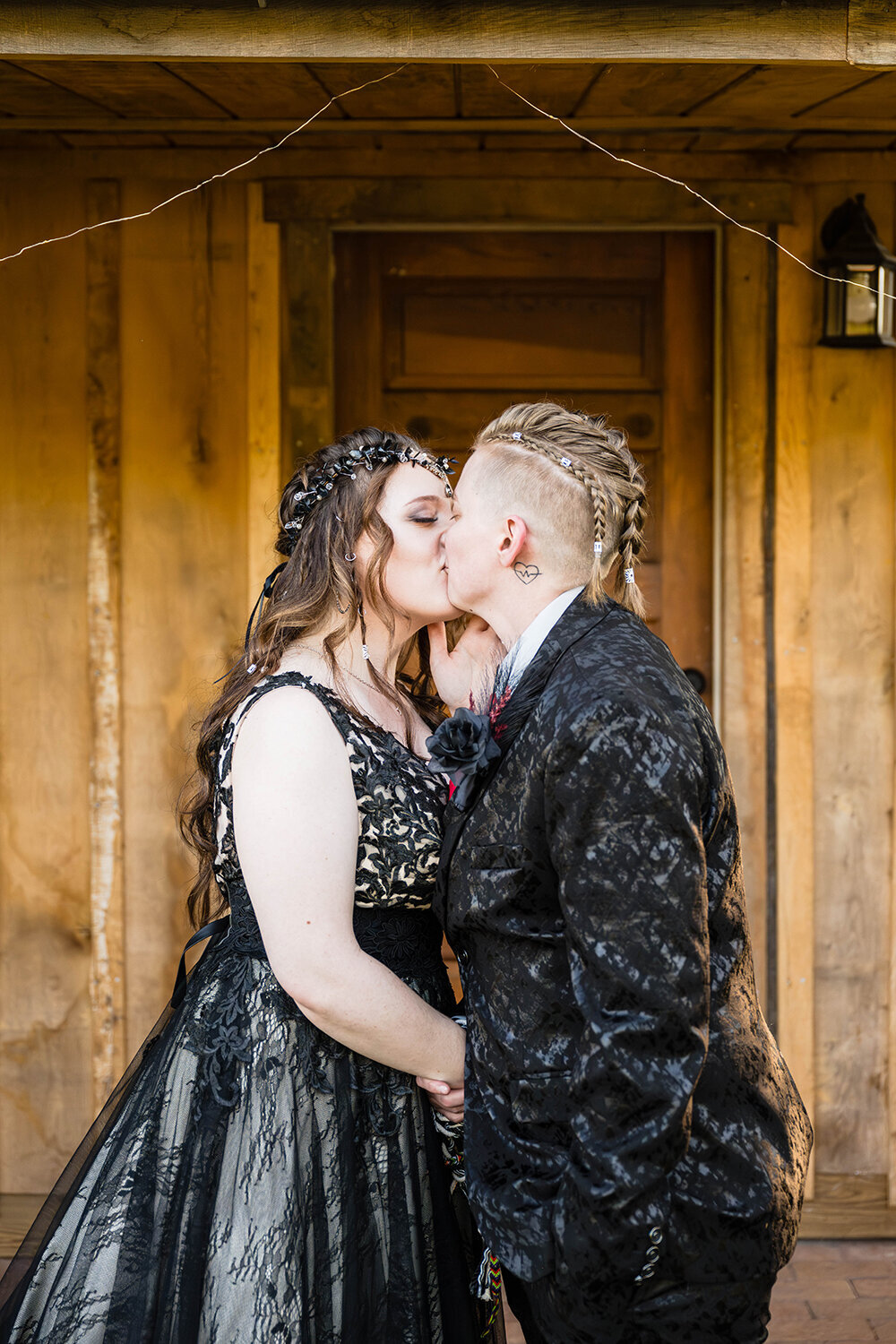 An LGBTQ+ couple on their elopement day go in for their first kiss following their handfasting ceremony. The pair stand in the backyard on the porch of an Airbnb they rented in Roanoke, Virginia.