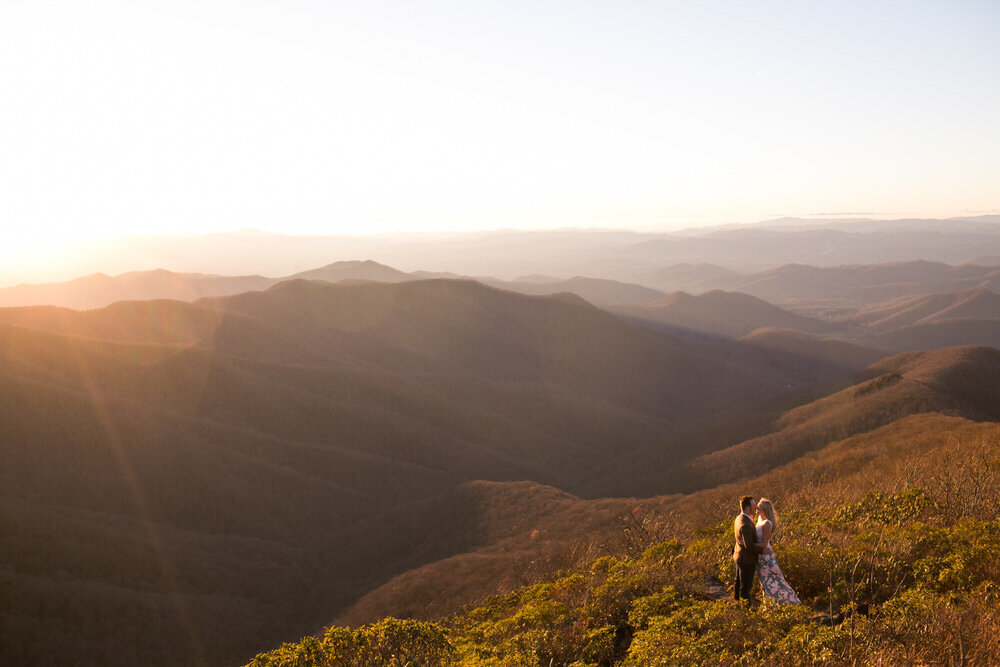 couple stands on a mountain at sunset