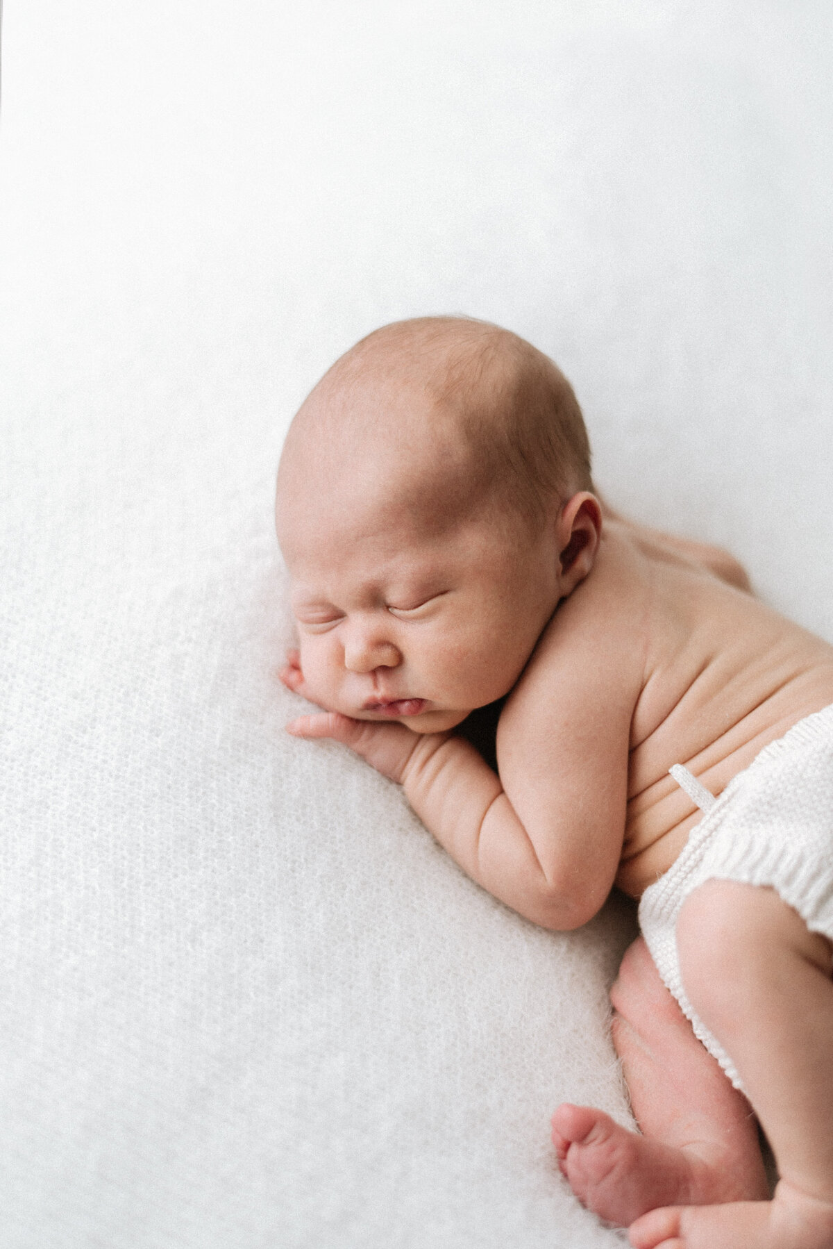 Baby boy sleeping on a white blanket at newborn photoshoot in Billingshurst