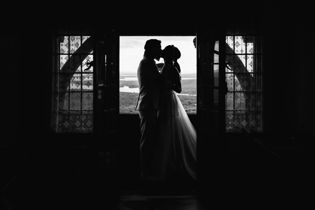 Groom kissing bride in windows at Mansion at Castle in the Clouds