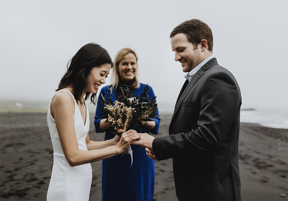 couple is exchanging rings and vows on their wedding ceremony in iceland