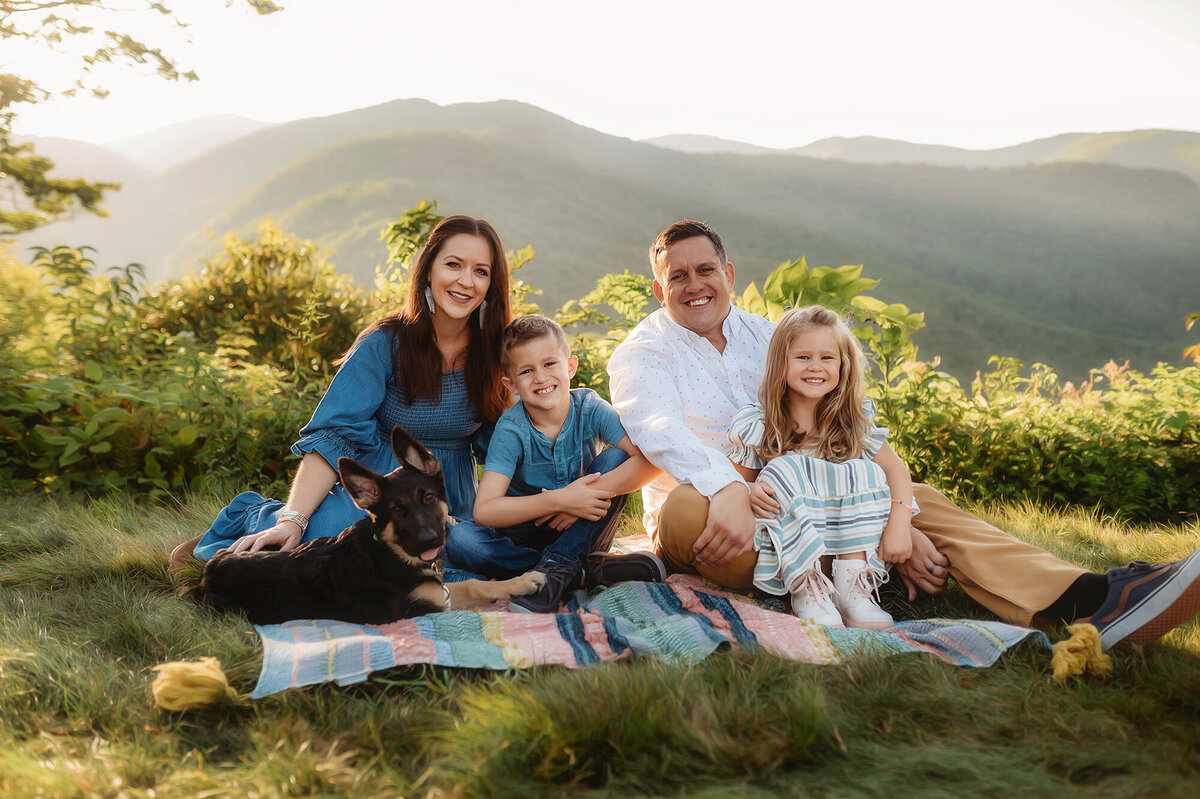 Family sits together on a mountain top during Family Photos on the Blue Ridge Parkway in Asheville, NC.