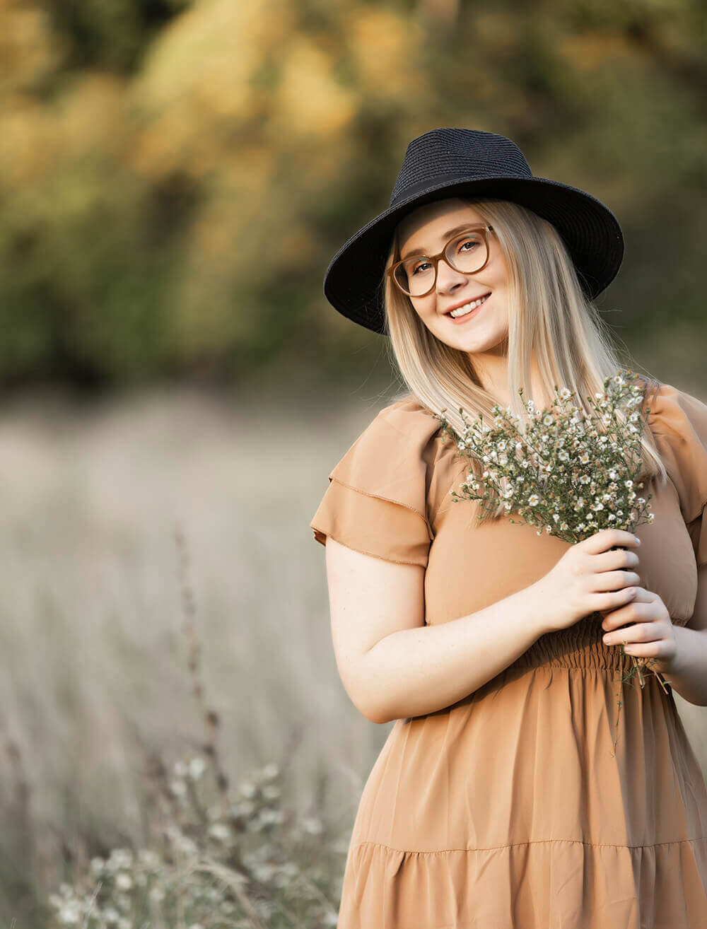Erie Pa senior with a hat holding flowers in a field in Erie pa