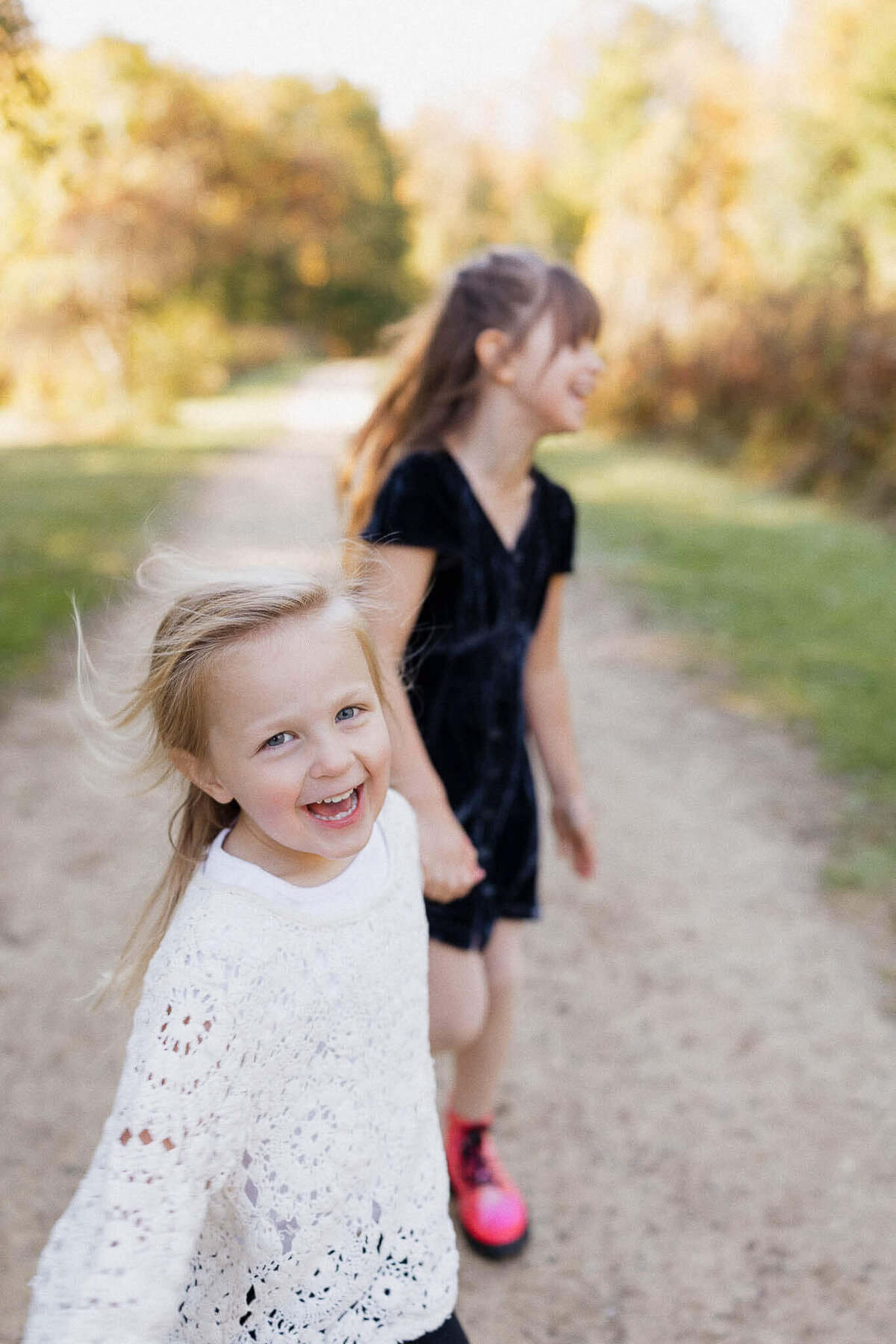 Sisters running and laughing in Cleveland Metropark trail during fall mini session.