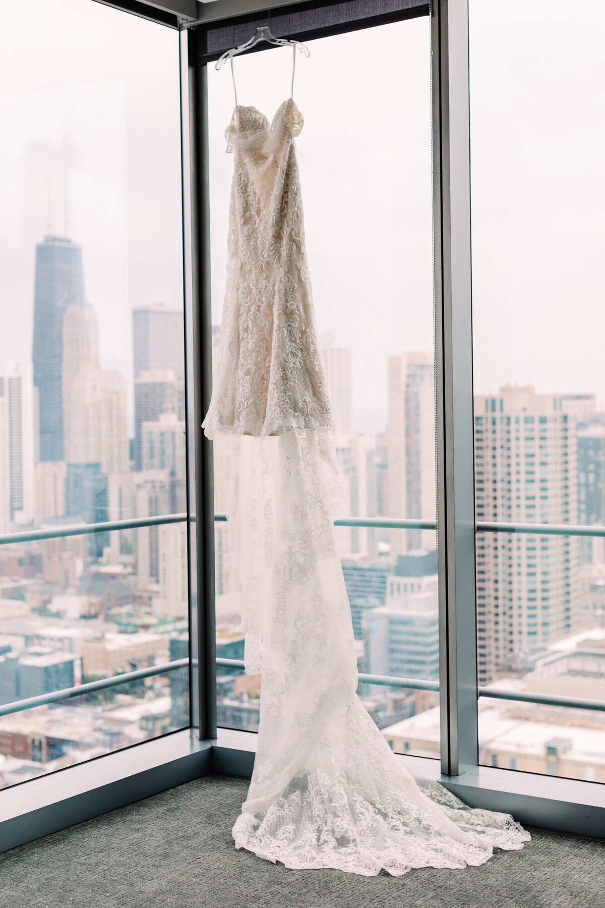 A stunning wedding dress hanging from the ceiling with the city skyline in the background, creating a breathtaking bridal moment.