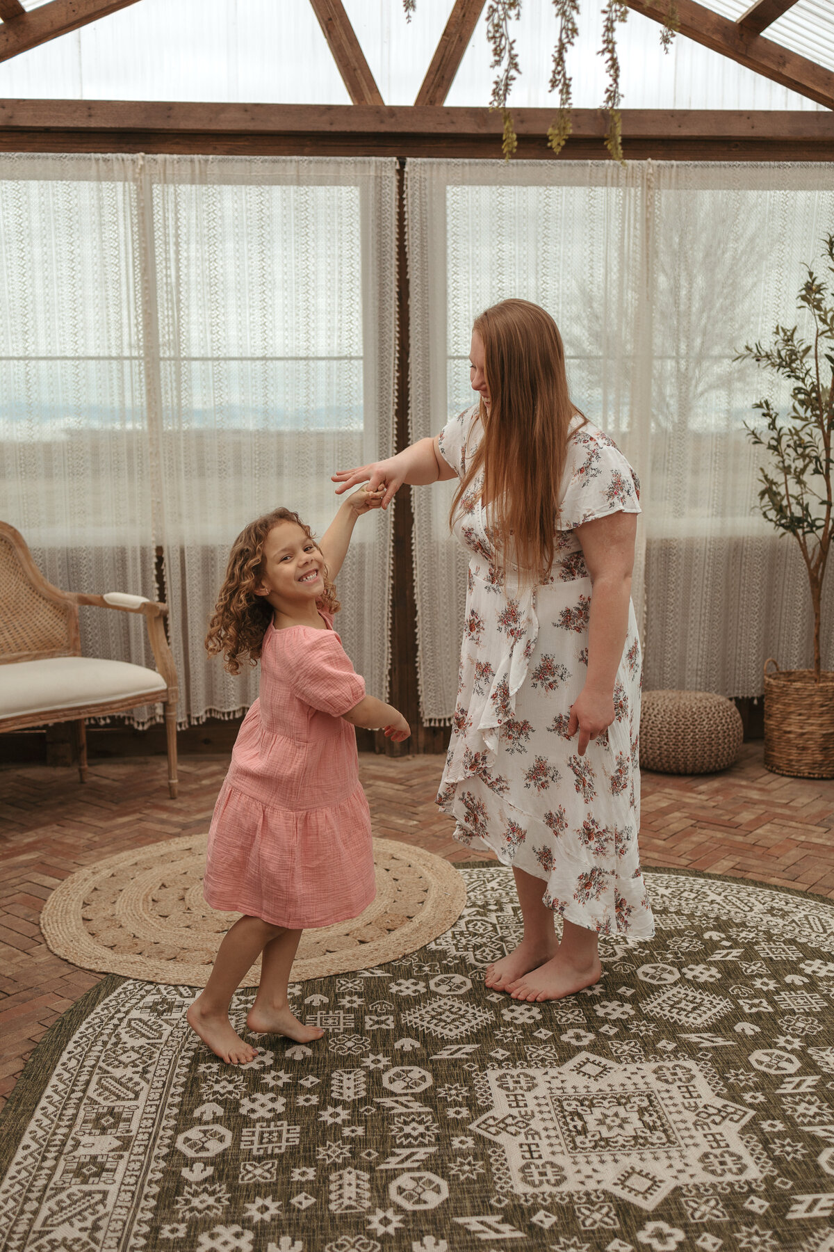 mom and daughter laughing while mom is holding daughters finger so she can spin during family session in longmont colorado