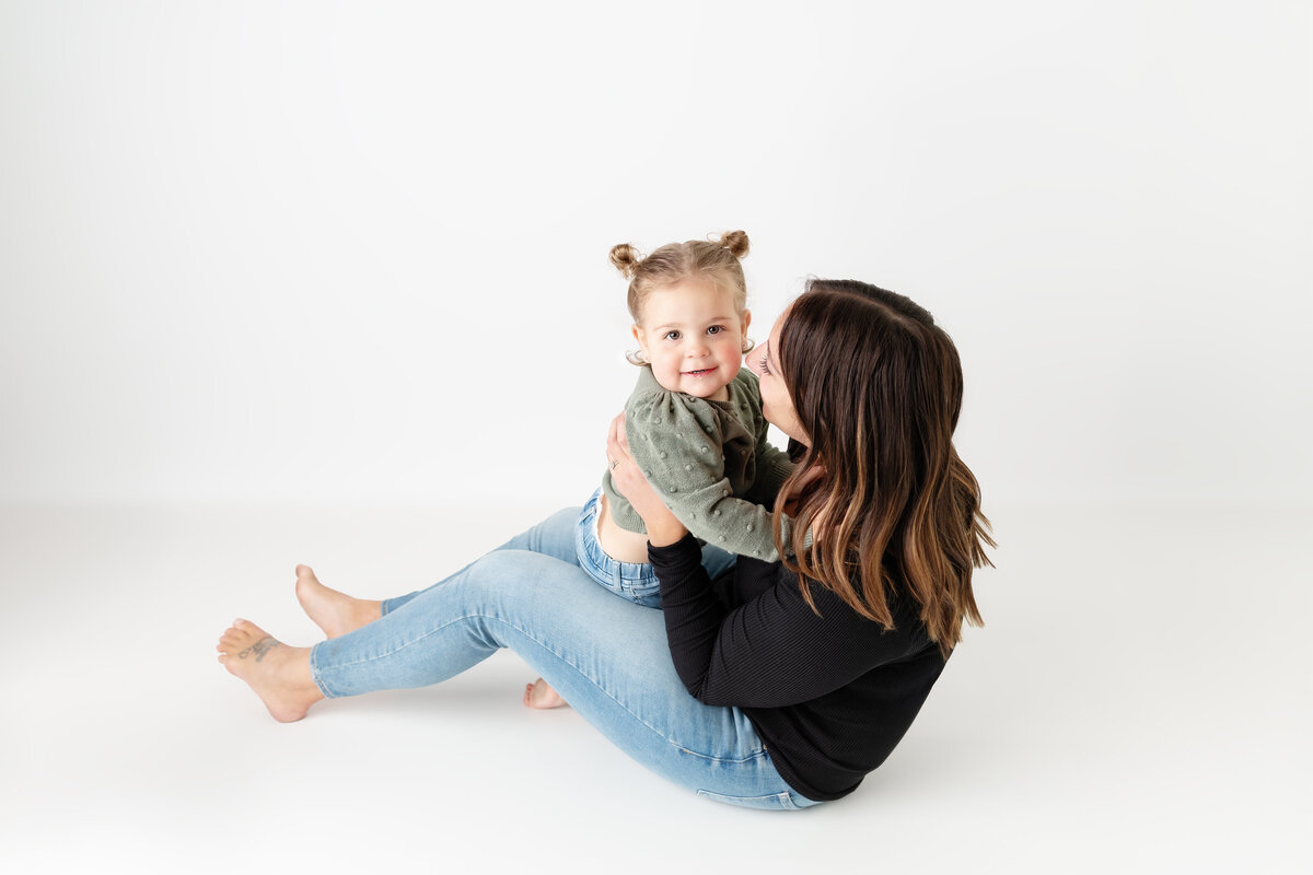 Mother and toddler daughter snuggling in a white background studio in Paris, Ontario portrait | Paris Ontario