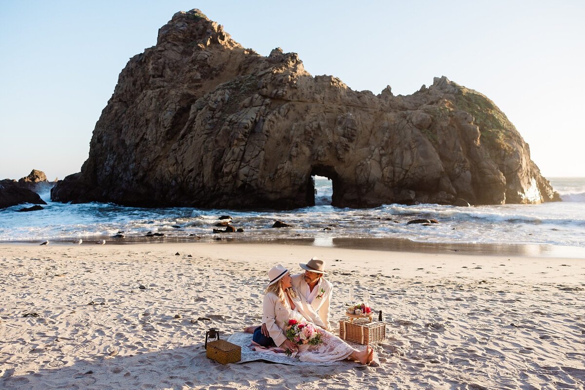 The bride and groom set up a beach picnic at Pheiffer Beach during sunset. 