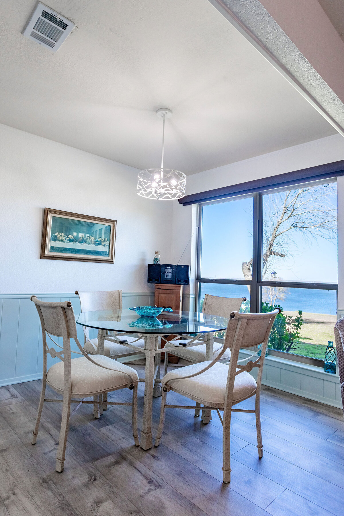 Dining room table that seats four with a beautiful view of the lake in this 2-bedroom, 2-bathroom lakeside vacation rental home for 6 guests on Tradinghouse Lake with privacy access to a fishing dock and boat launch pad, ping pong table, gazebo, free wifi and free parking in Waco, TX.