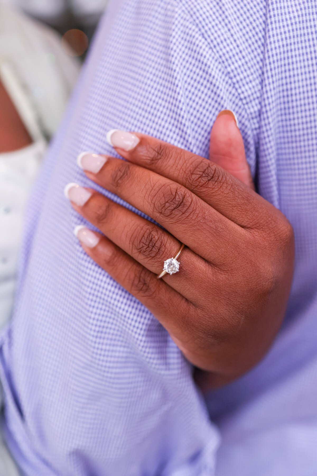 solitarie diamond engagement ring on womans hand while holding finacee's arm