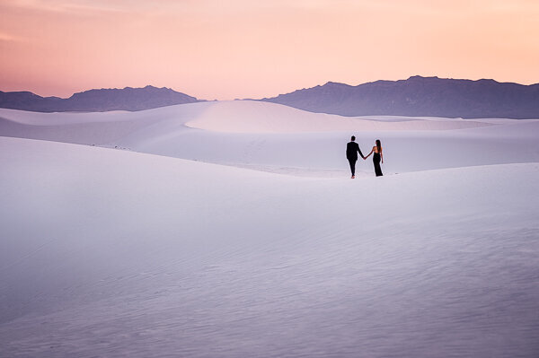 Engaged couple walking on a dune at white sands national park