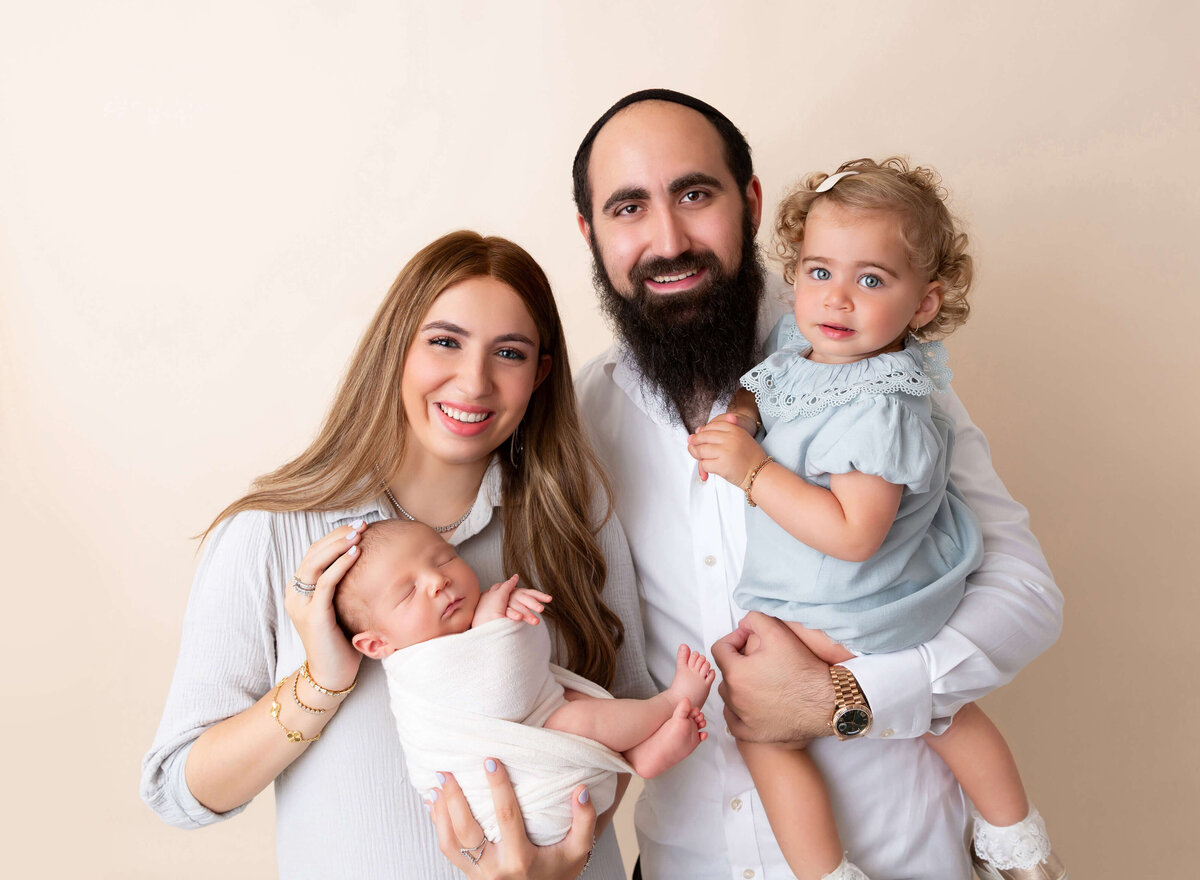 Family newborn portrait in Brooklyn studio, captured by NYC newborn photographer — parents holding their baby boy

