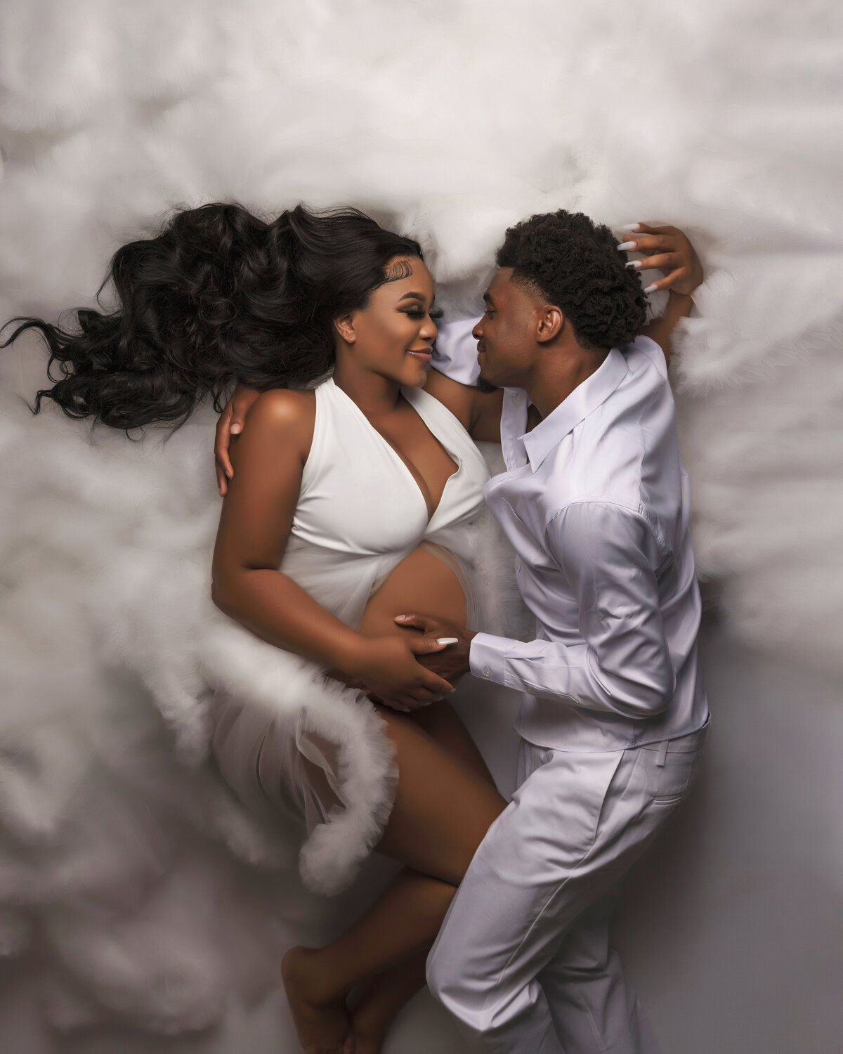 mom and dad to be posed on floor laying down wearing white in suit and fluffy couture gown near seattle