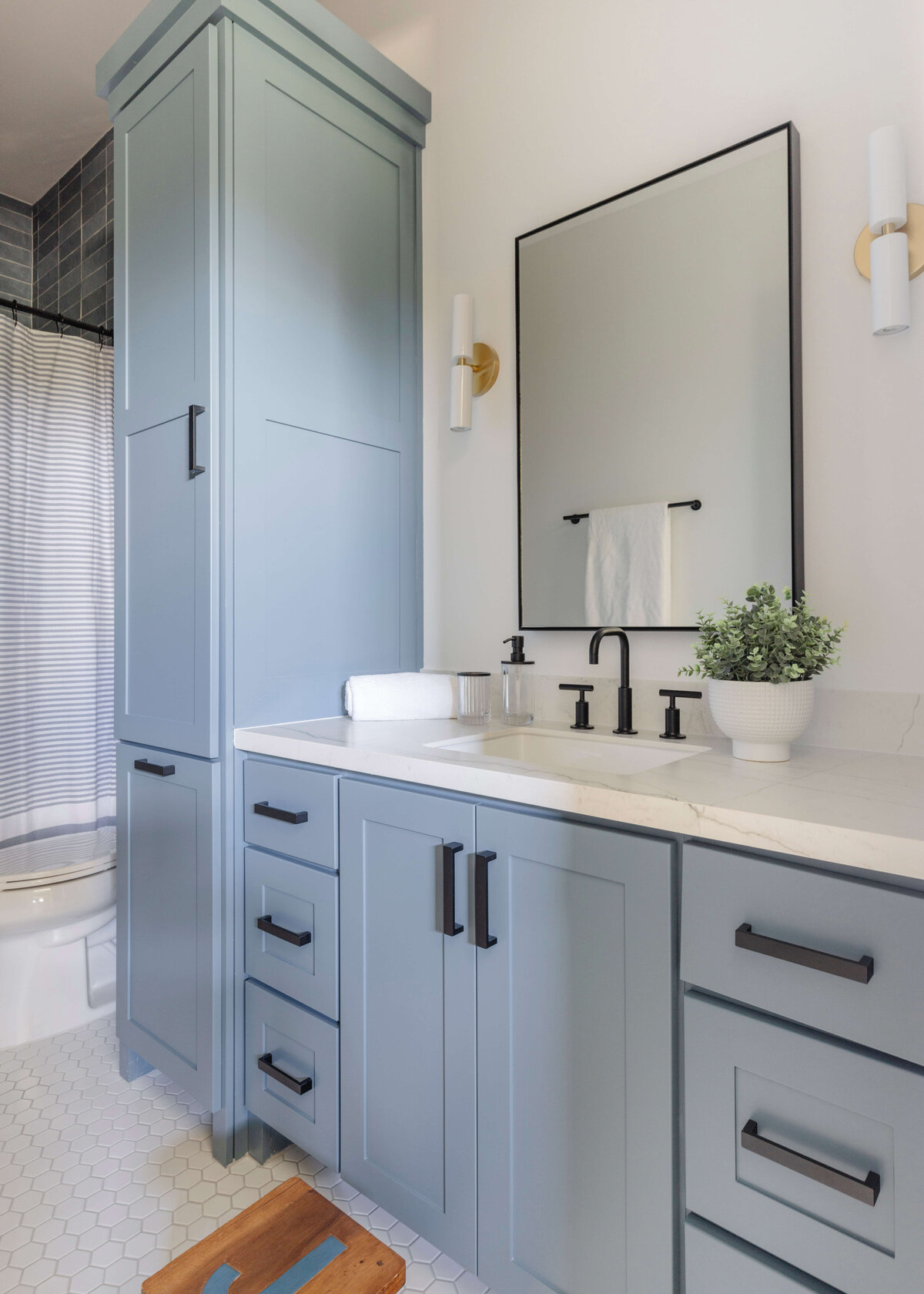 oyster creek studios hughes blue vanity with black hardware in bathroom with white tile