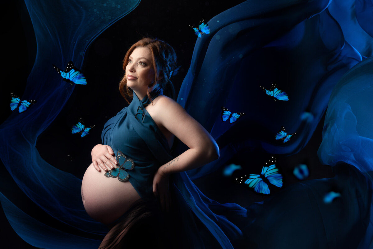 Maternity portrait of a mom-to-be wrapped in blue fabric with butterflies