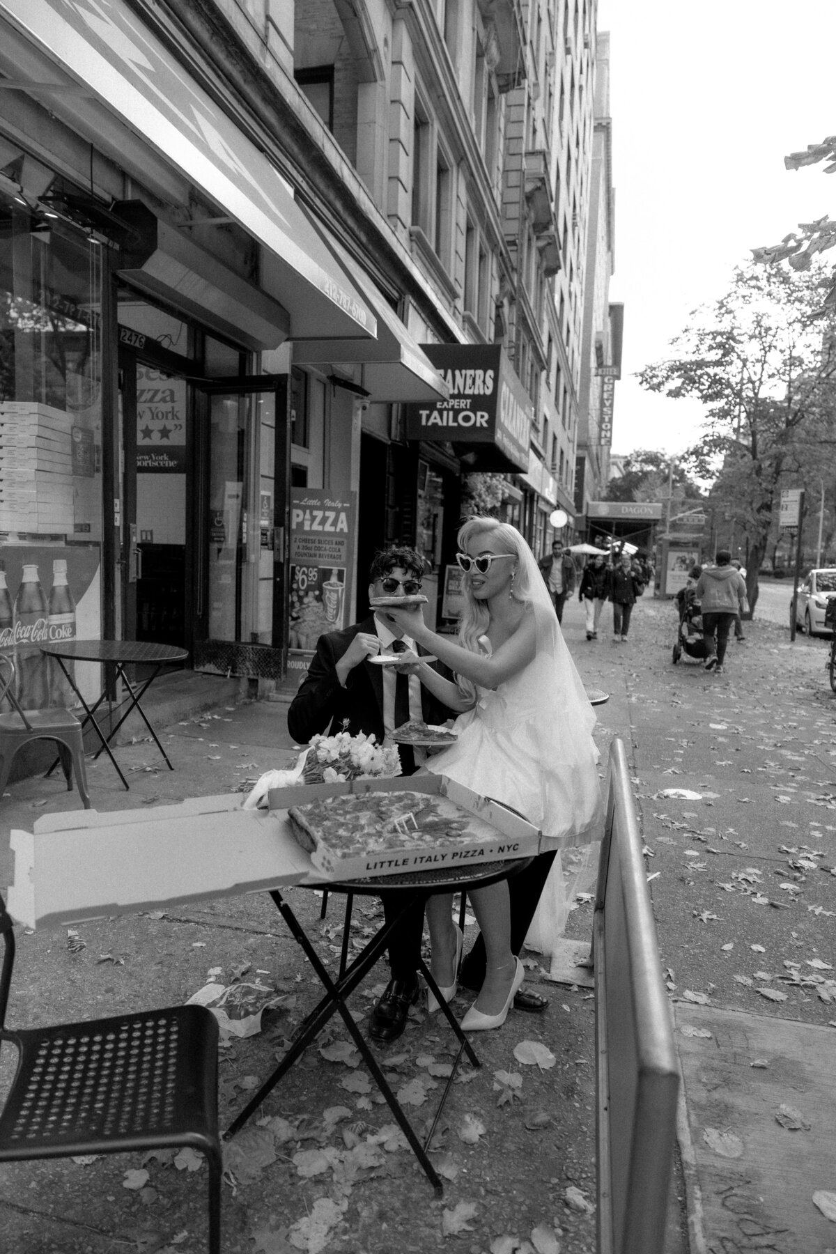 Bride and groom toasting their pizza slices together in celebration of their NYC elopement.