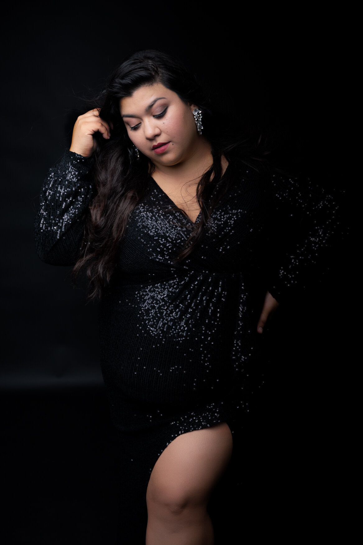 Latina woman posing wearing a black gown showing her left leg
