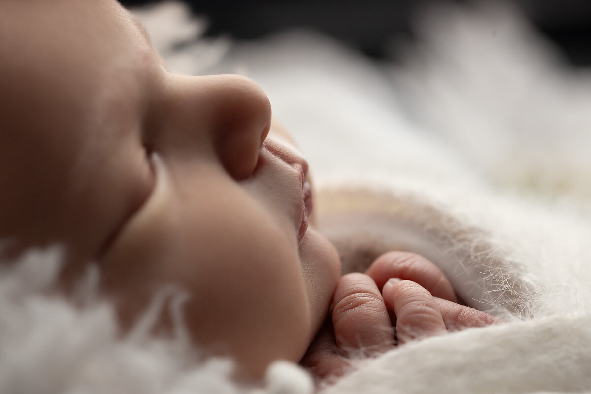 Macro image of a newborn’s delicate lips and tiny fingers, highlighting baby details captured by a newborn photography studio specializing in timeless newborn pictures.