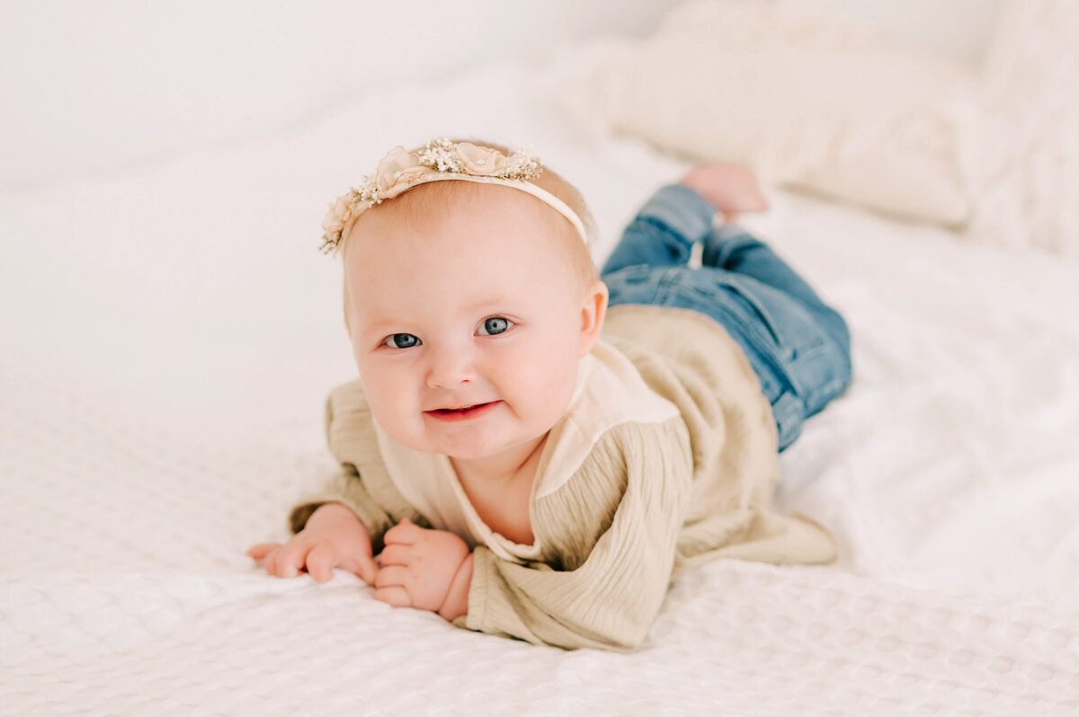 little girl smiling on bed in  Branson MO baby photography studio