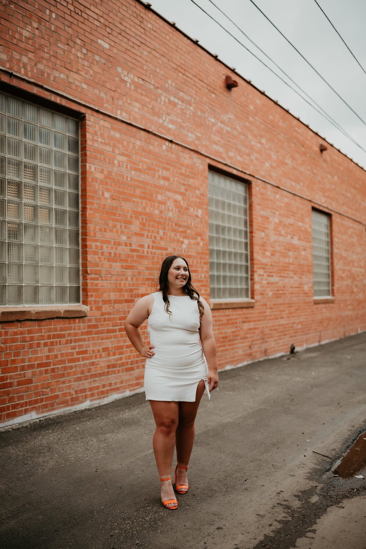 downtown senior session of girl in white dress by brick wall, amarillo texas senior