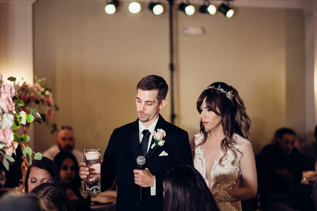 Wedding Photograph Of Groom Looking At The Glass He's Holding While Speaking Los Angeles
