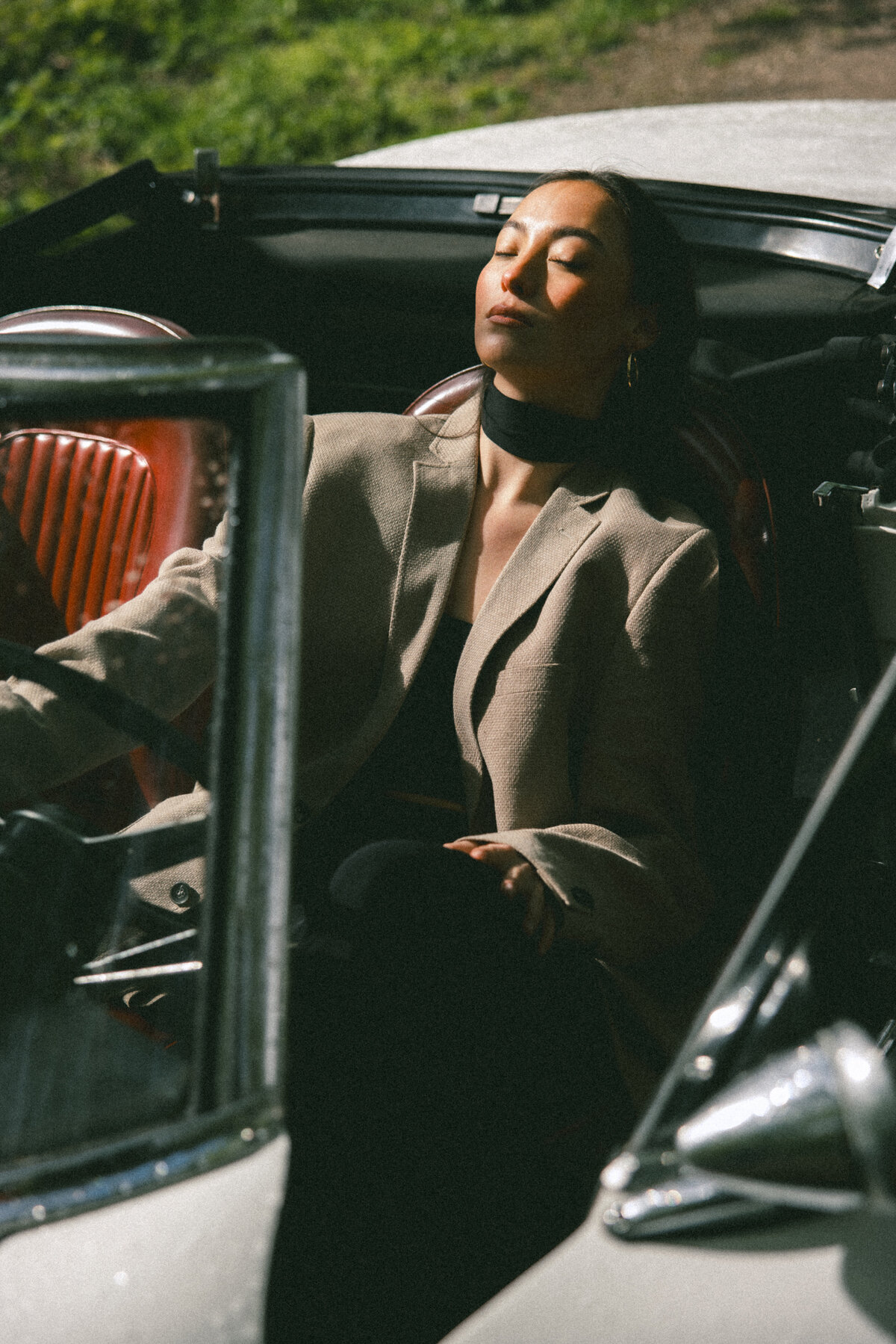 Bathed in sunlight, this image captures the subject relaxing in the driver’s seat, eyes closed in a moment of peace. The soft light accentuates the textures and colors, giving the photograph a warm and serene atmosphere, photographed by Bo Eppink.