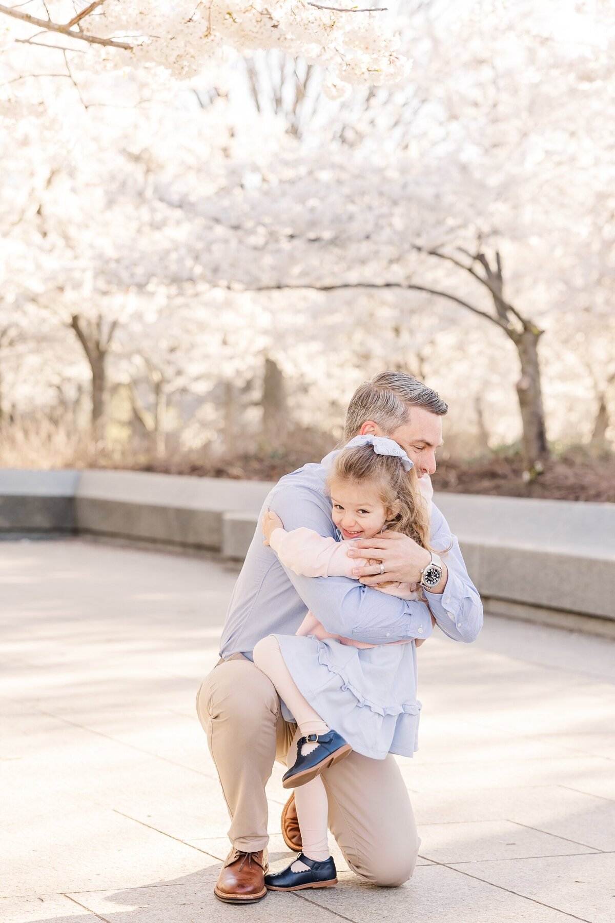 Little girl hugging her dad among the cherry blossoms  by Erin Thompson Photography