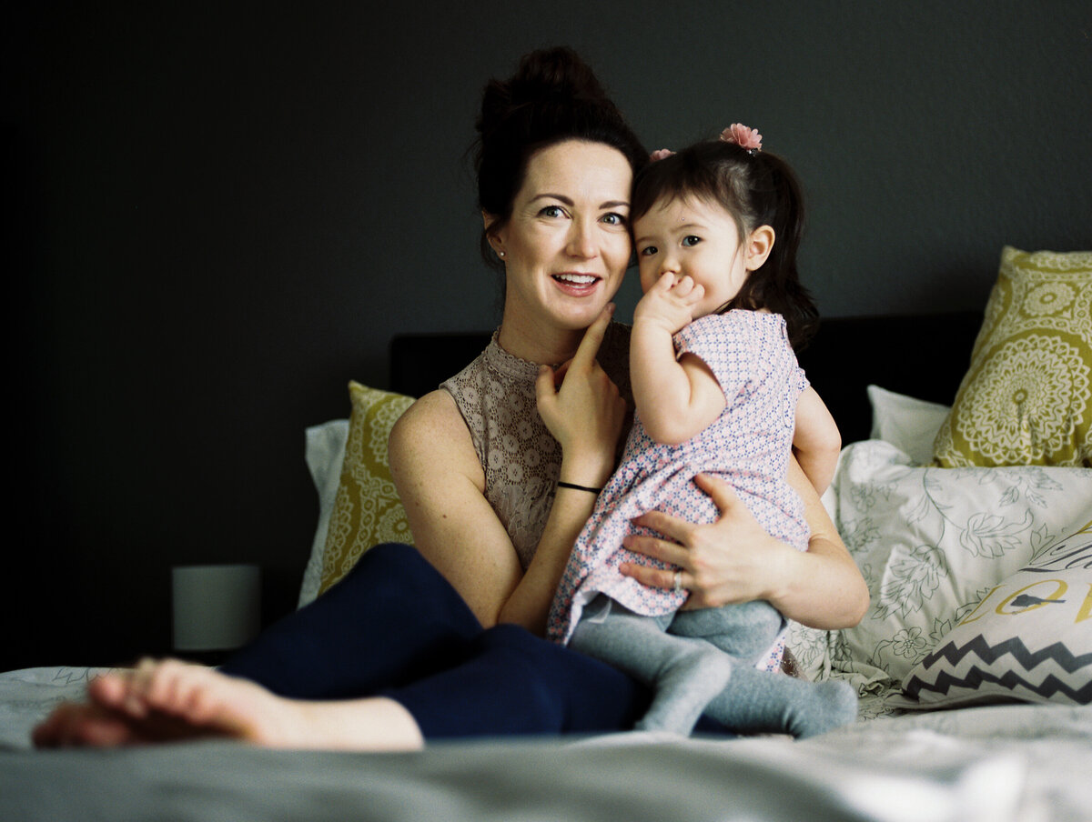 a mom holds her toddler daughter and both touch their faces