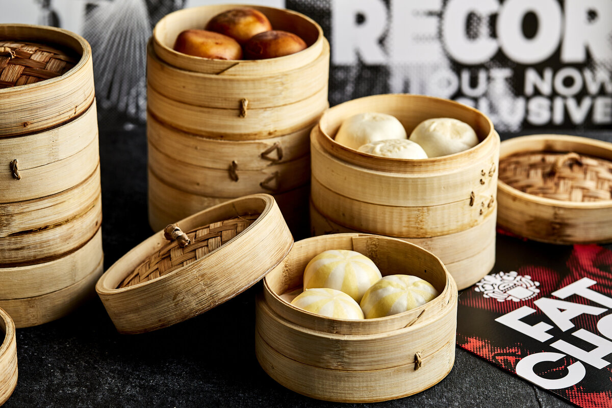 Large round dumpling steaming baskets with various types of dumplings in them.