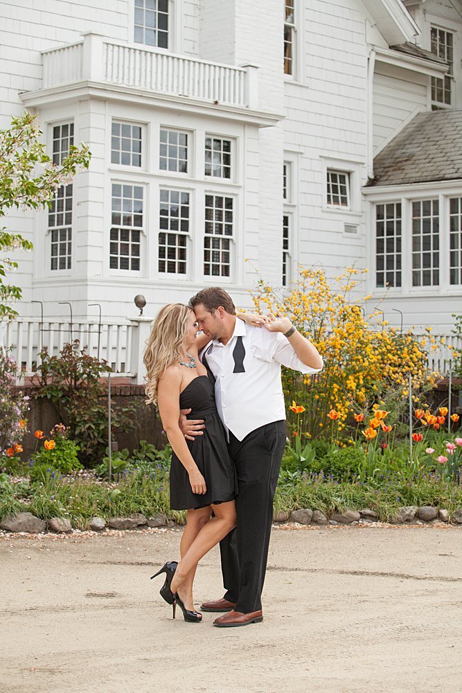 Engaged couple dancing near white mansion