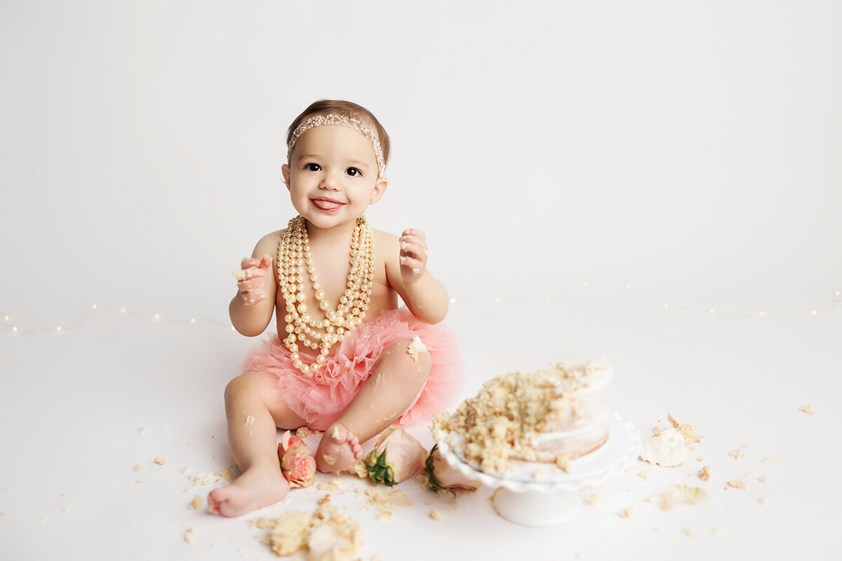 Beautiful one year old sitting in her smashed cake
