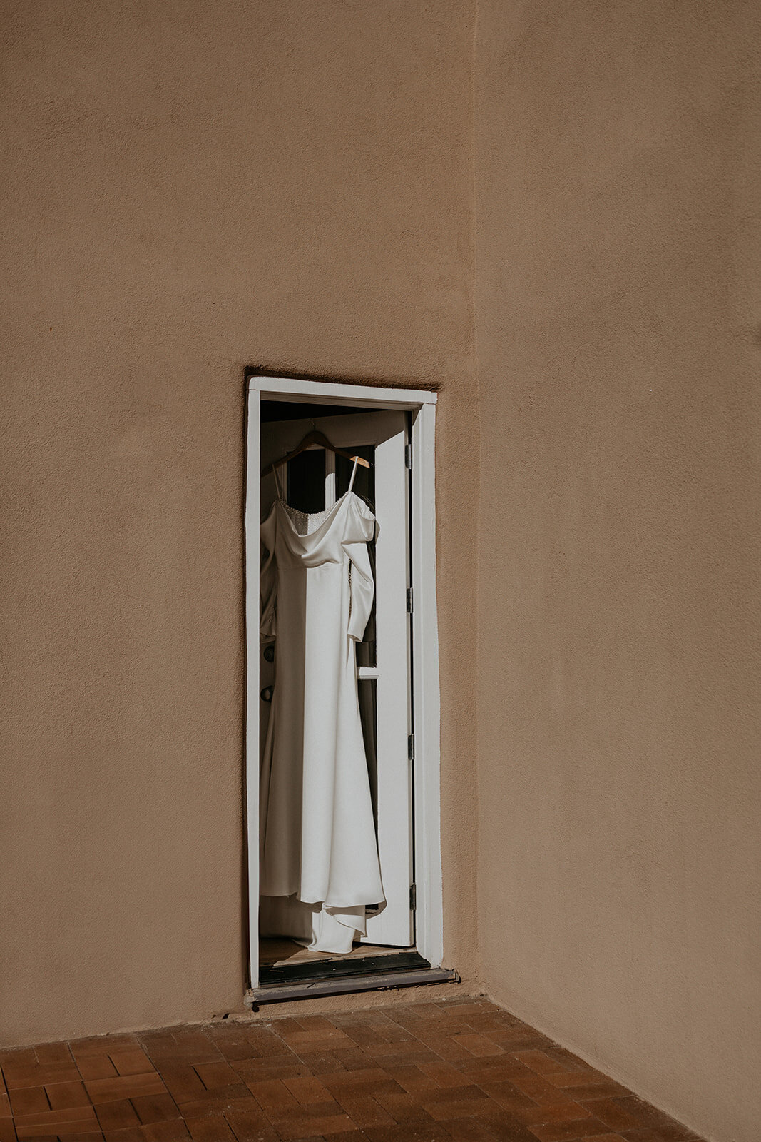 brides dress hanging in a doorway