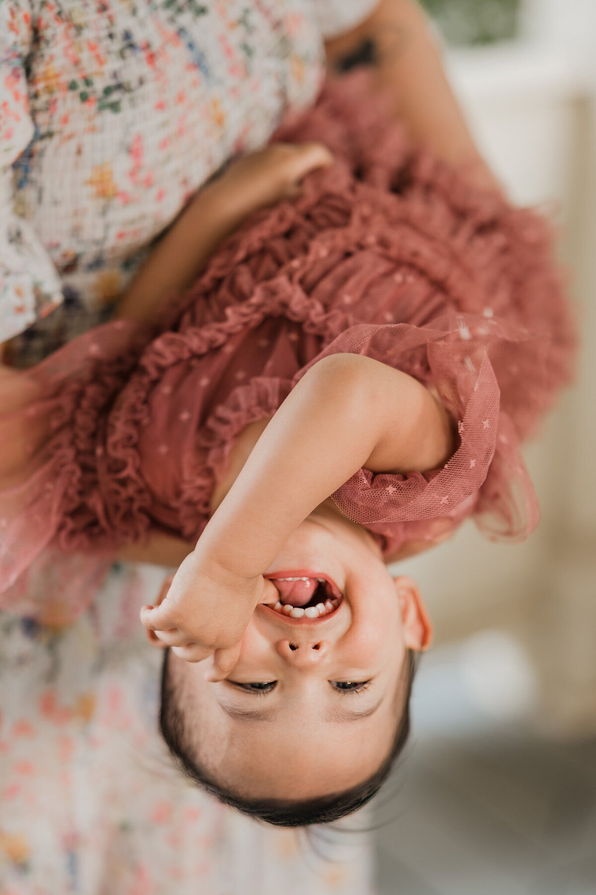 Image of a little girl being dipped upside down by her mom. Family photographer by Cassey Golden.