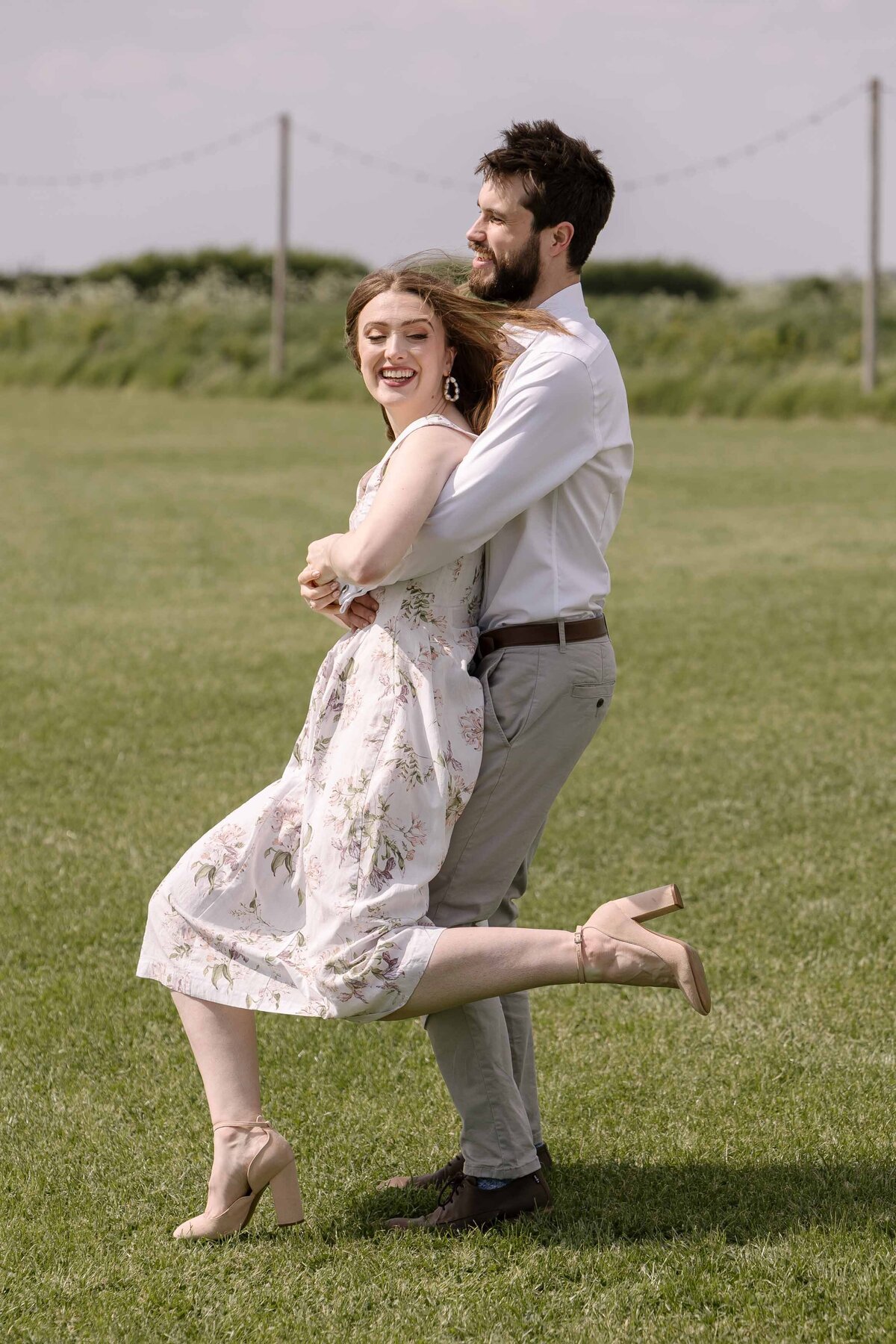 An engaged photo spinning around in a field