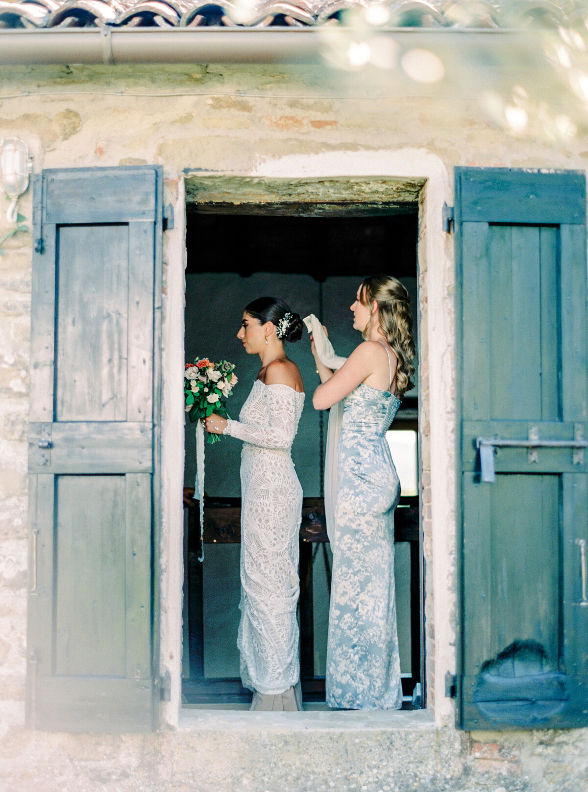 Film photograph of maid of honor putting in bride's veil before her Italy wedding photographed by Italy wedding photographer at Villa Montanare Tuscany wedding