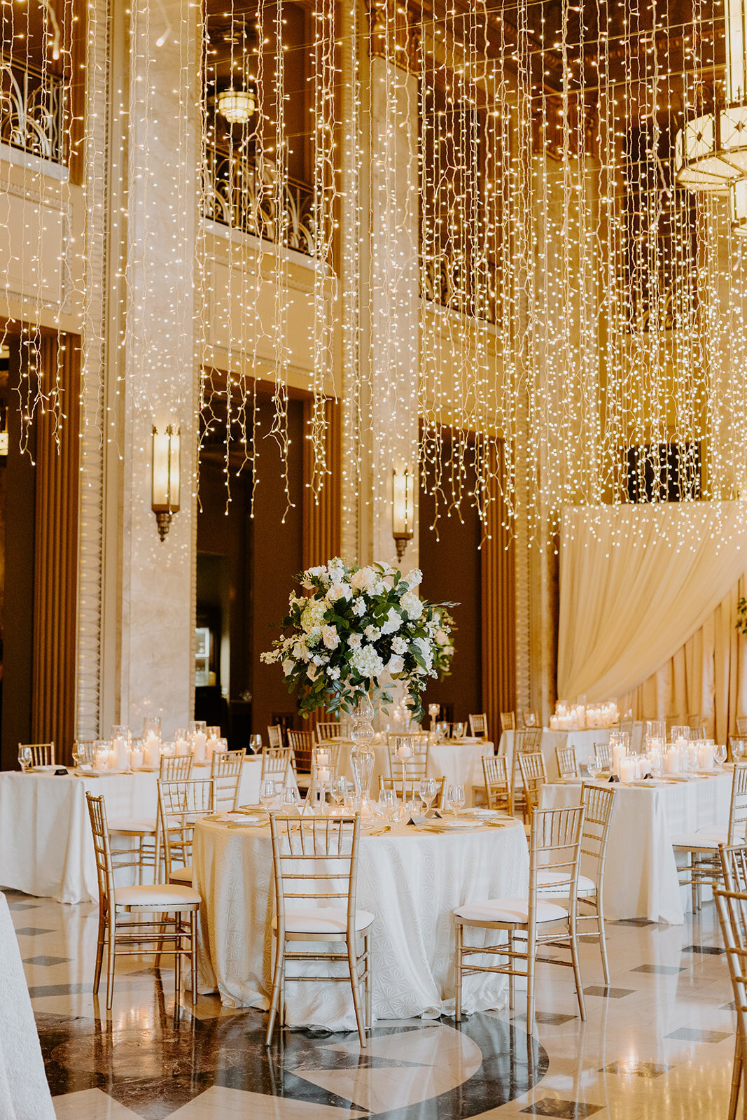 Wedding reception details with florals, gold chairs, and dangling twinkly lights