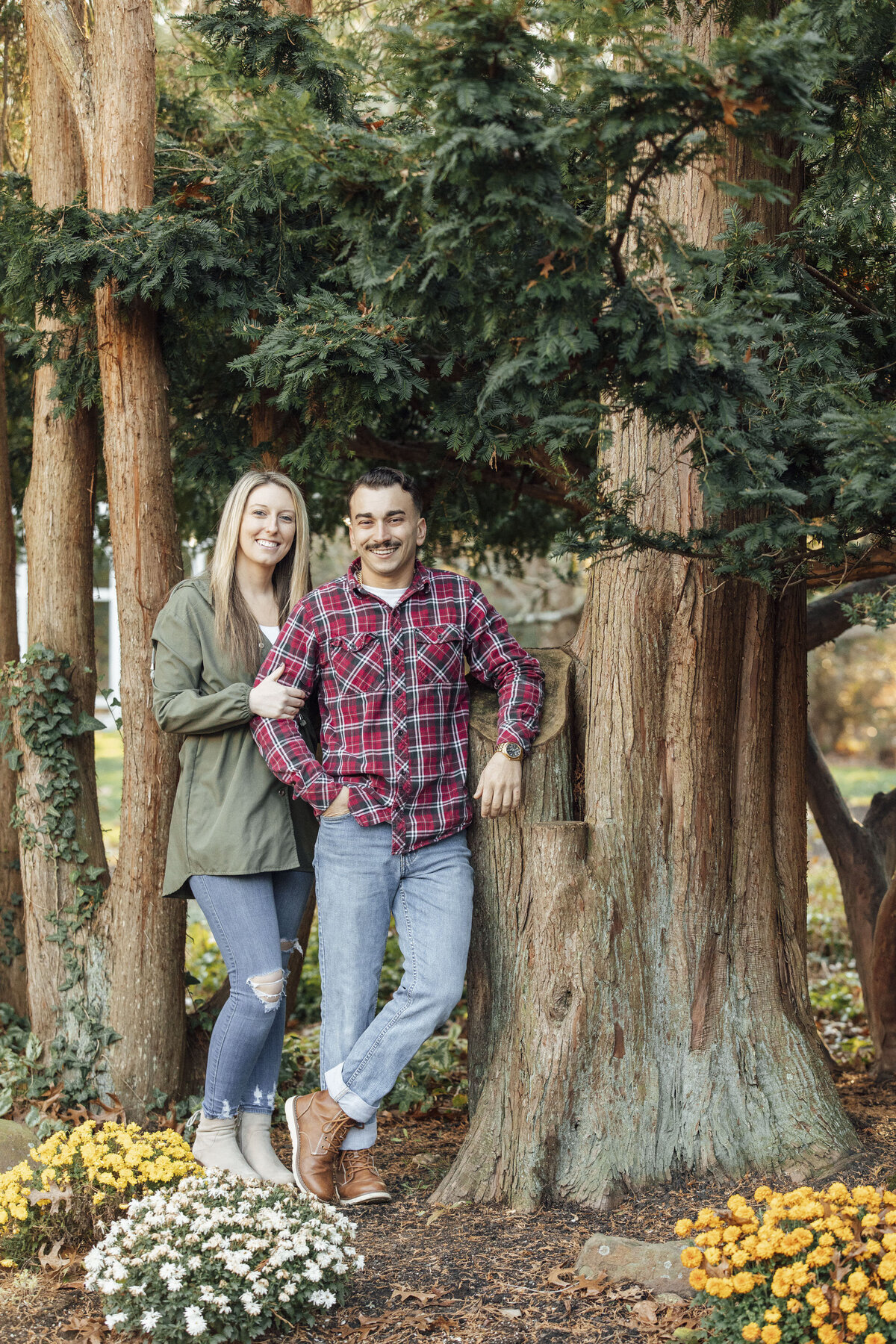 Couple leaning against tree during fall engagement photo at Sayen House and Gardens in Hamilton Township New Jersey
