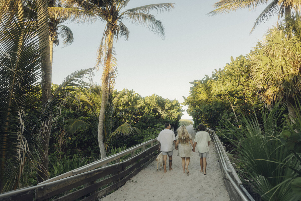 family holds hands on the beach