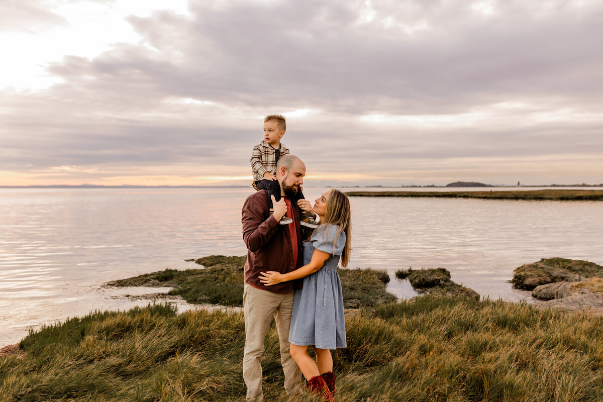 little boy on dads shoulder as they look at mom