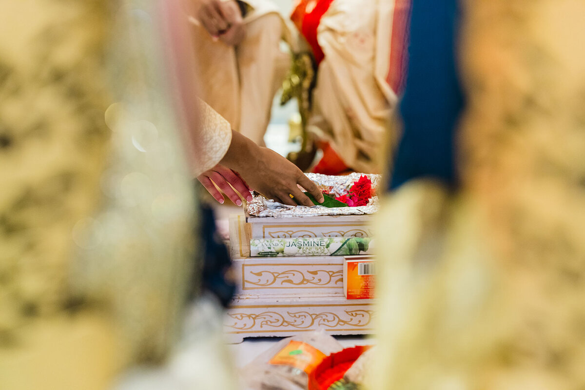 A view through a decor element of a bride placing her hand on a ceremonial object