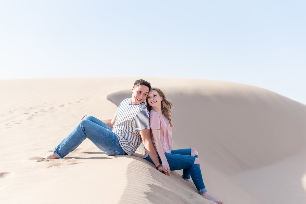 couple sits back to back at glamis sand dunes