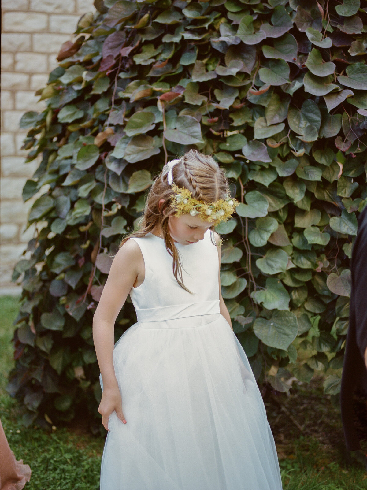 a flower girl in a sweet flower crown plays with her dress after a wedding ceremony at Christ Church in Detroit