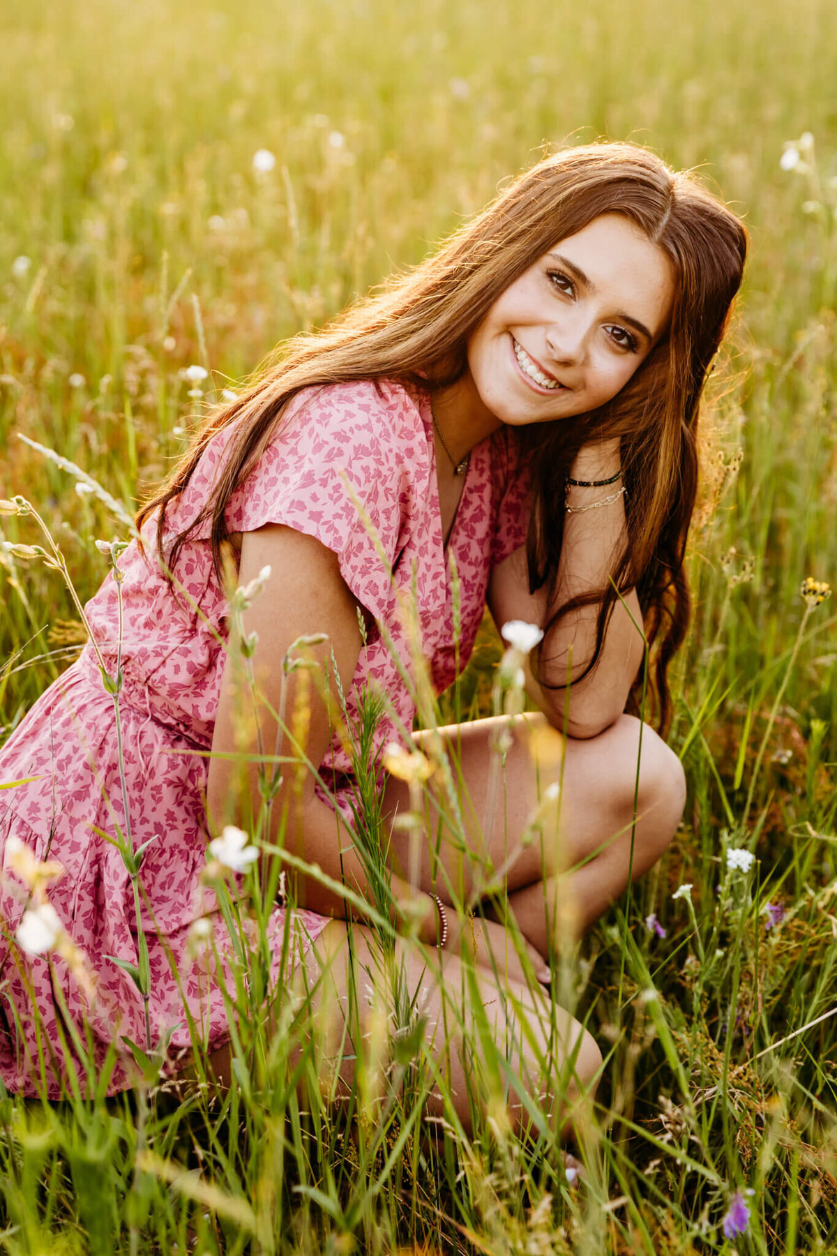stunning Green Bay senior girl resting her head on her hand as she kneels in a field that is filled with flowers