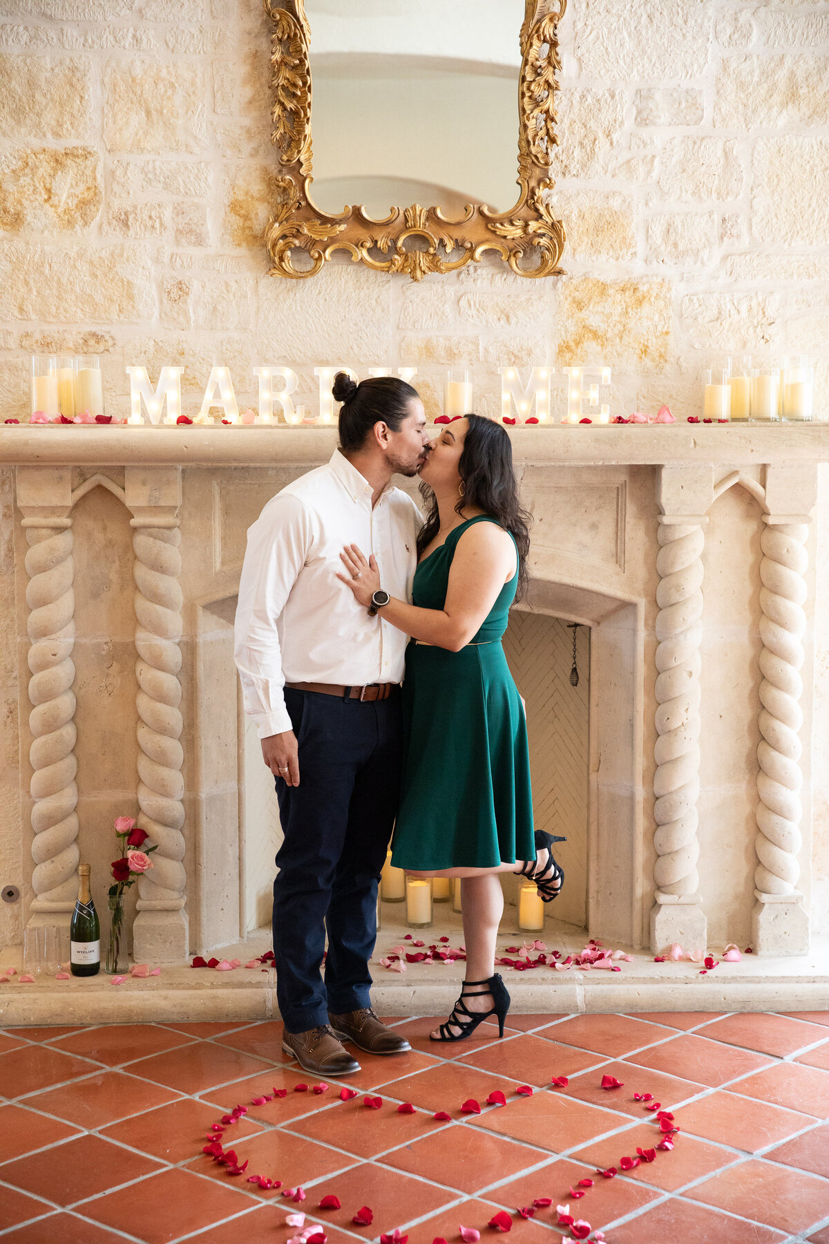 An engaged couple sharing a passionate kiss in front of a cozy fireplace, captured by an Austin wedding photographer.