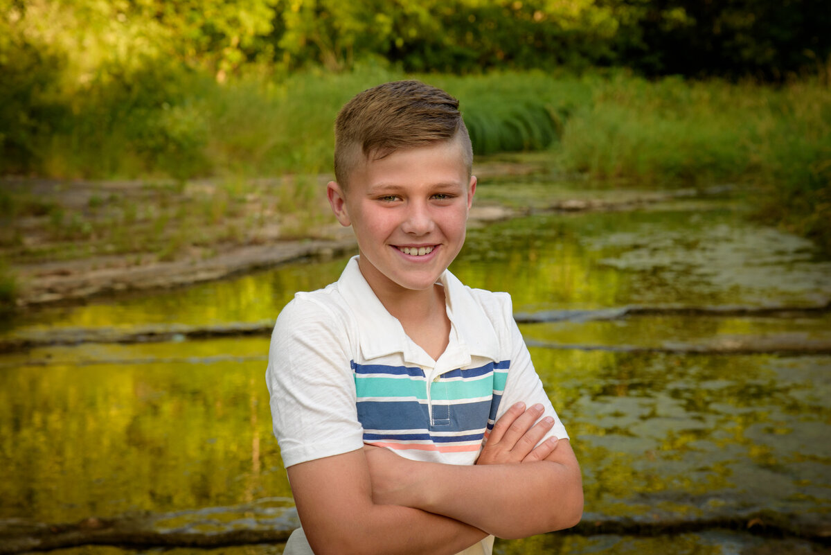 Portrait of eleven year old boy smiling at the camera standing near the creek at Fonferek Glen County Park near Green Bay, Wisconsin