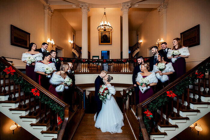 wedding-party-stands-on-staors-and-looks-at-bride-and-groom